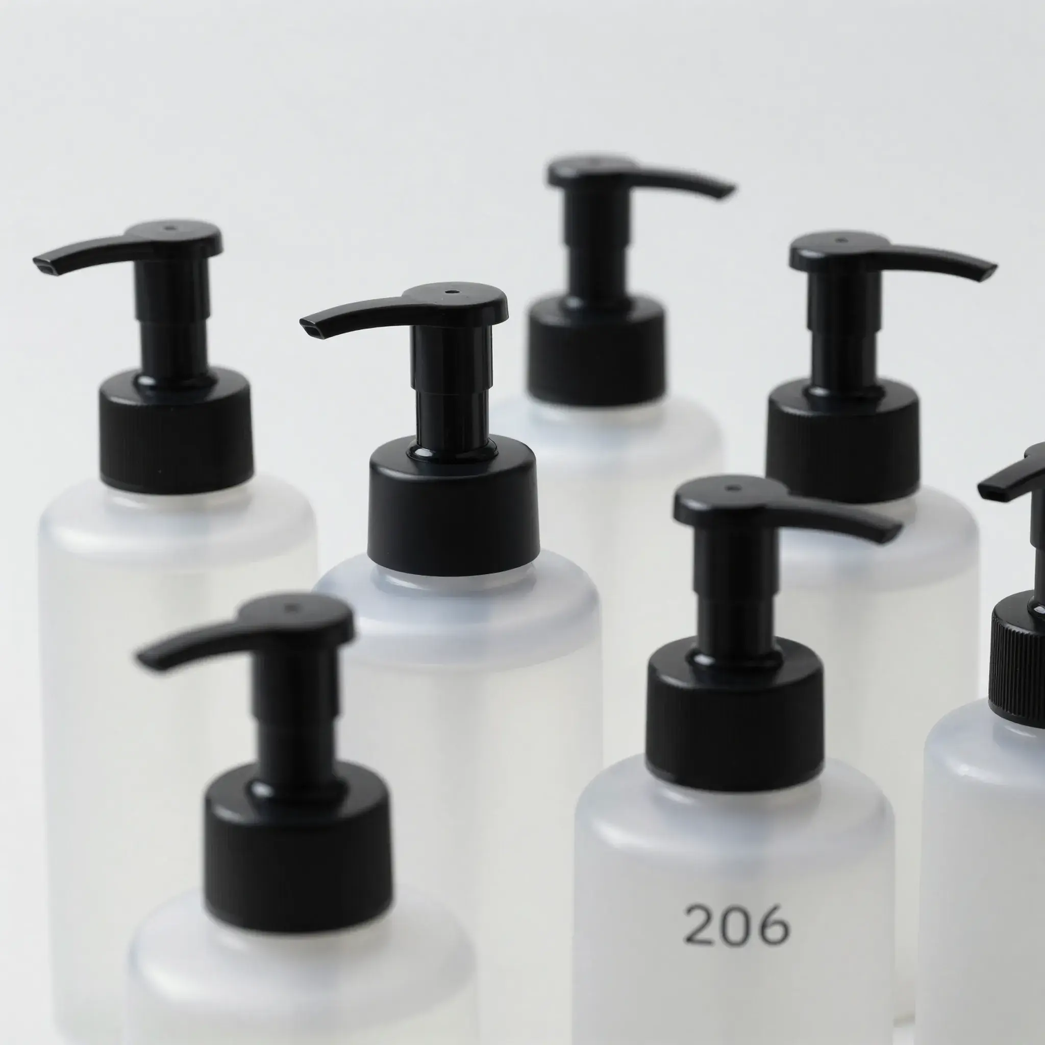 Black pump dispensers on frosted plastic cosmetic bottles